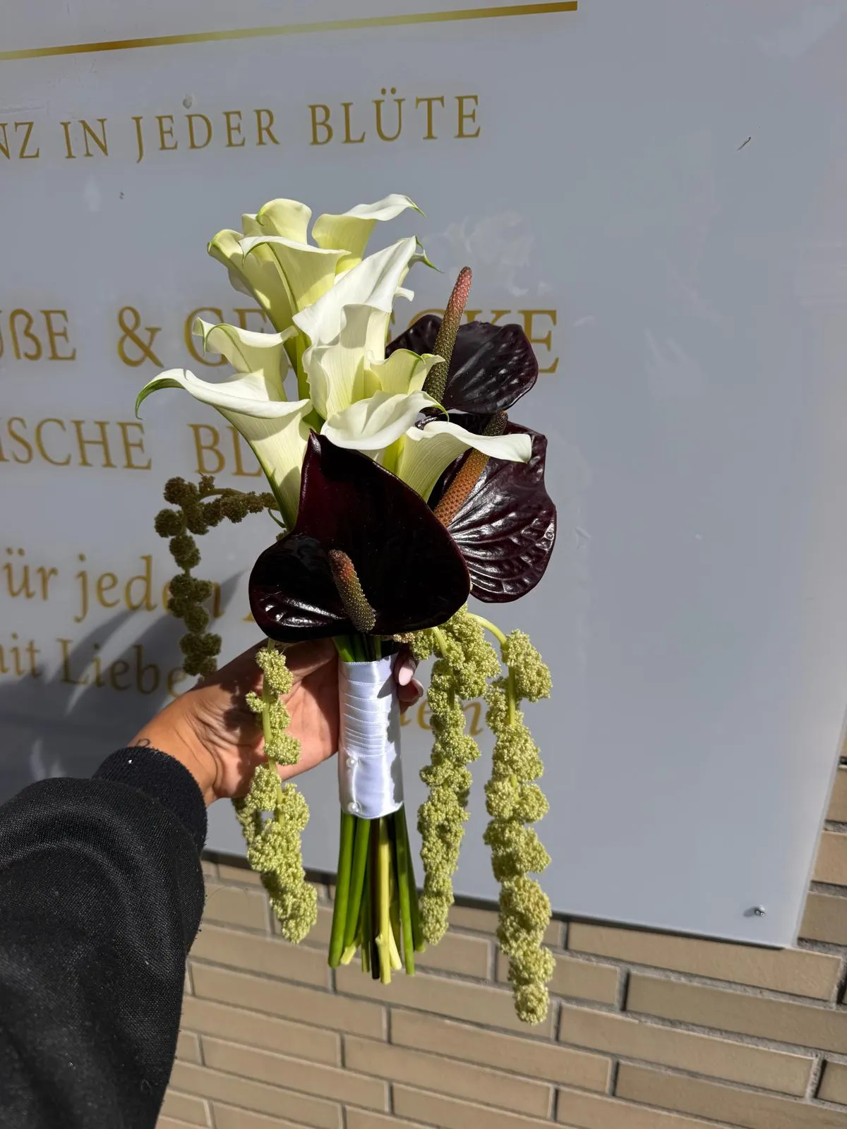 Moderner Strauß aus weißen Calla-Lilien und bordeauxroten Anthurien